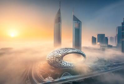 Aerial view of the Museum of the Future at sunset with the Emirates Towers in the background.