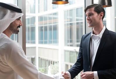 Business professionals greeting each other with a handshake in a modern office