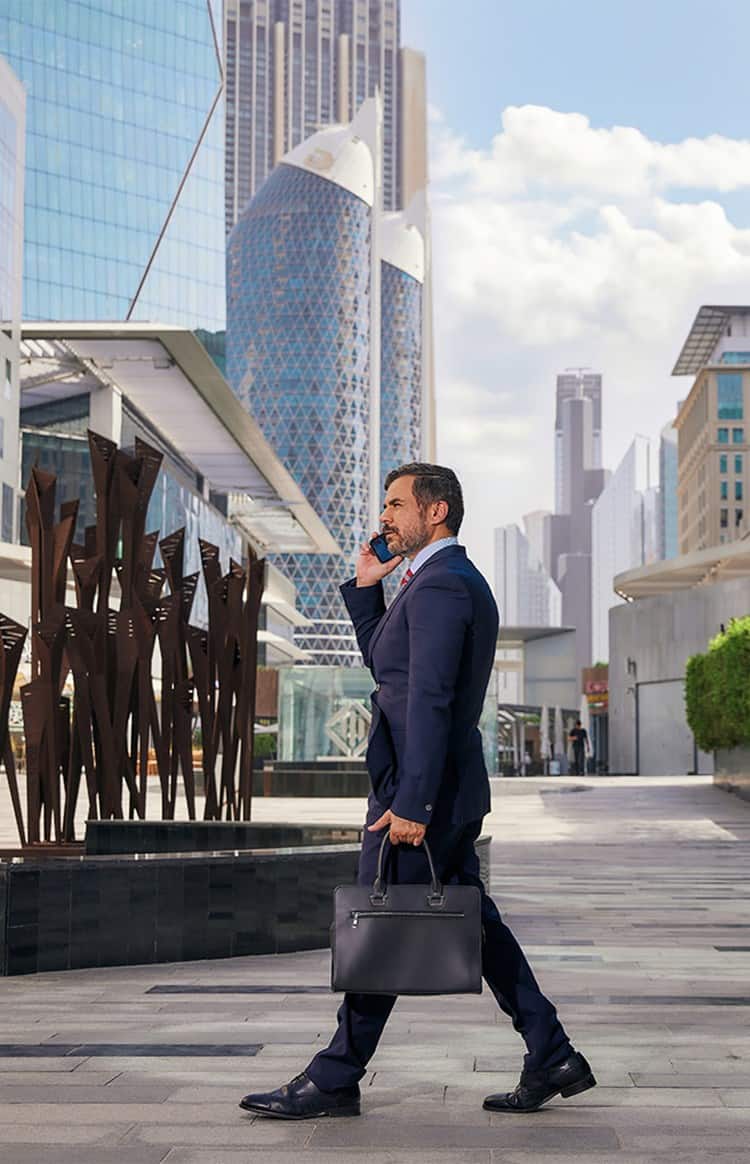 Business professional walking through Dubai's modern financial district with skyscrapers in the background