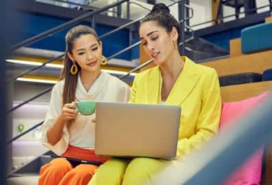 Two professionals discussing work while using a laptop