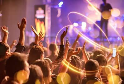 Audience raising their hands during a live concert with colourful stage lighting