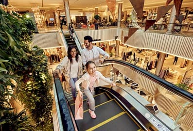 Family riding an escalator inside a modern shopping mall